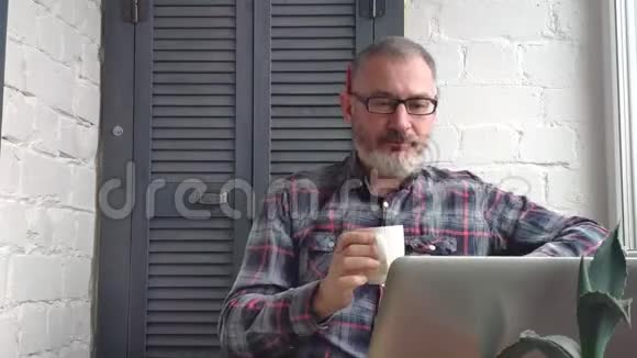 一位留着胡须的男会计师在一台笔记本电脑后面的家里工作在极简主义的室内环境背景下做了一份报告视频的预览图