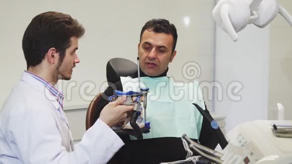 专业牙医向他的成熟病人展示牙模视频的预览图