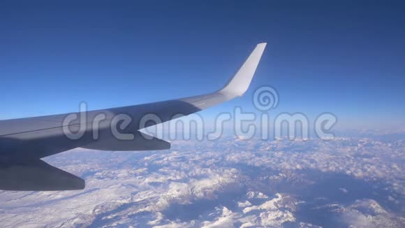 飞机的机翼可见于云层上方的飞机窗口视频的预览图