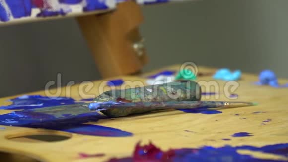 画家工作场所一个木制的调色板上有油漆上面有一个用来画画的铲子和一个刷子艺术绘画视频的预览图