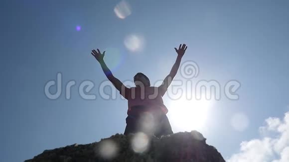 站在岩石边缘的年轻人的视线在天空和背景上升起他的双手慢慢慢慢视频的预览图