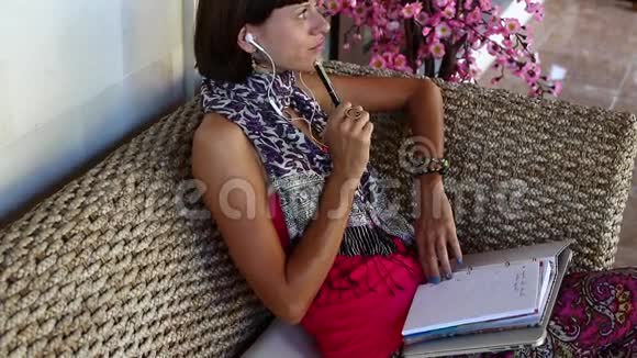 有笔记本电脑思考和笔记的女人在别墅外面的教练笔记本上巴厘岛视频的预览图