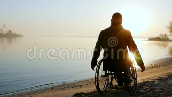 残废人手举起来在轮椅上日落孤独的残疾人视频的预览图