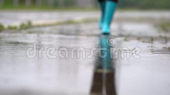 穿着蓝色橡胶靴的女人在水坑上跳跃的特写镜头视频的预览图