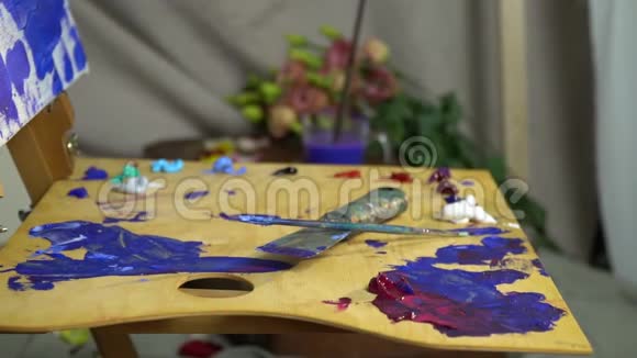 画家的工作场所在木制的调色板上涂着油彩上面有一把用来画画的铲子和一个画家画笔一个视频的预览图