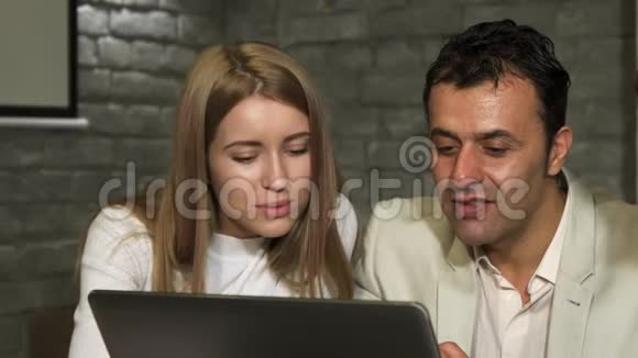 成熟的商人和他的年轻同事在笔记本电脑上工作视频的预览图