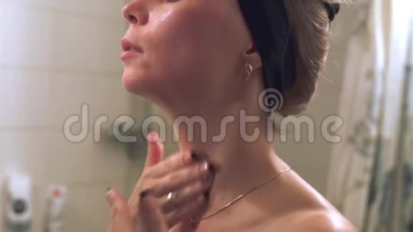 在浴室里做面部按摩的年轻女子闭上眼睛视频的预览图