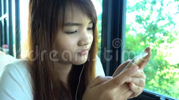 女人在智能手机上使用应用程序在咖啡馆里喝咖啡微笑着在手机上发短信视频的预览图