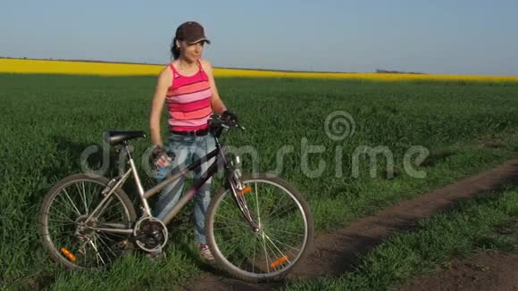 骑自行车的女孩喝水一个骑自行车的农村年轻女子一个运动女孩在喝水视频的预览图