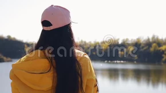 穿黄色夹克的女游客享受大自然的休息视频的预览图
