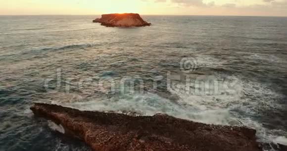 海上的石岛日落时相机飞到岛上视频的预览图