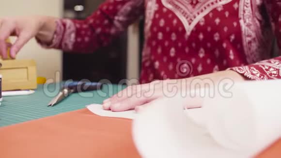 中年妇女用别针将纸样钉在织物上视频的预览图