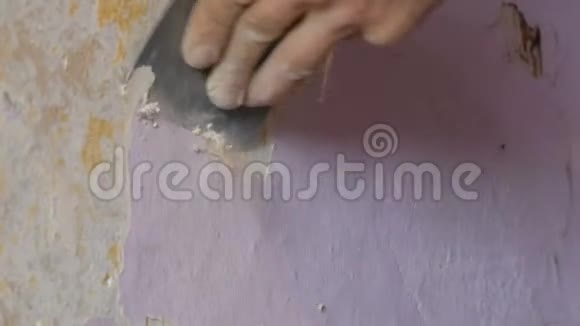 男建筑工人用特制的刮刀从墙上撕下或剥下旧的粉红色壁纸视频的预览图