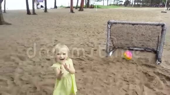 漂亮的小女孩站在迷你足球门附近拍视频的预览图