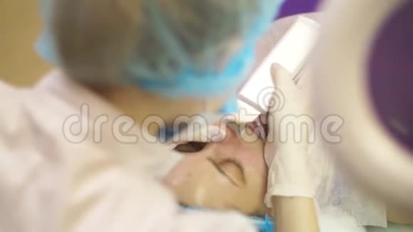 在一家美容诊所用激光从一名年轻妇女的皮肤上取出黑点视频的预览图