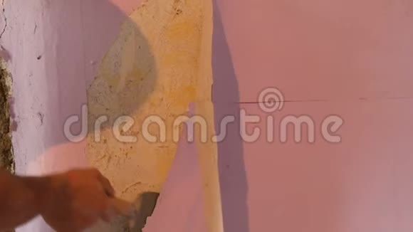 男建筑工人用特制的刮刀从墙上撕下或剥下旧的粉红色壁纸视频的预览图