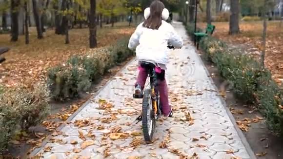 一个高加索儿童在秋天公园骑自行车视频的预览图