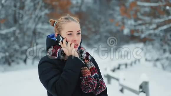 冬季公园里的女孩谈论手机视频的预览图