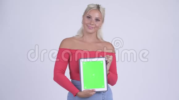 一位年轻漂亮的金发美女一边看着数码平板电脑一边思考视频的预览图