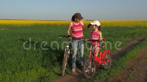 在农村骑自行车的女人带着孩子性质的体育家庭妈妈和女儿在田里骑自行车视频的预览图