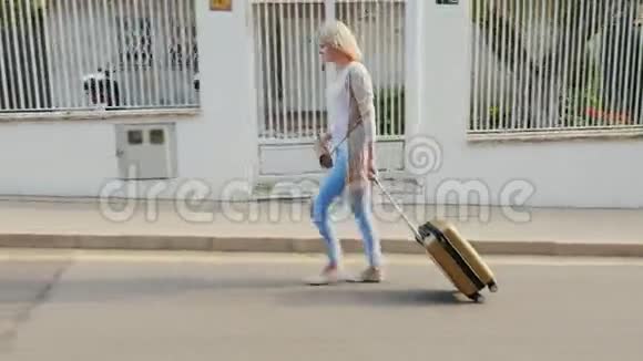 带着旅行袋的女人沿着度假区走它沿着旅馆的地面沿着街走视频的预览图
