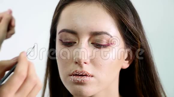 化妆师画一个年轻女孩的眉毛深色专业油漆慢动作视频的预览图