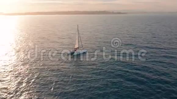 空中观景双体船经过海上相机靠近飞过船只日落时美丽的景色视频的预览图