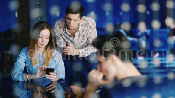 一群年轻人正在咖啡馆里休息一对年轻夫妇正在看智能手机屏幕上的东西在视频的预览图