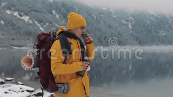 冬天美丽的山穿着黄色冬装的徒步旅行者在外面喝热茶或咖啡视频的预览图