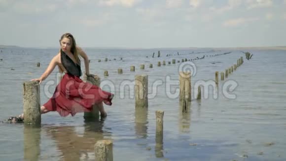 金发碧眼穿着一件红色的衣服穿在泥里站在河口拿着盐池的木柱视频的预览图