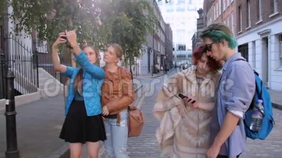 三个快乐时髦的年轻女人和一个男人在伦敦的街道上行走做自拍笑和开玩笑关于视频的预览图
