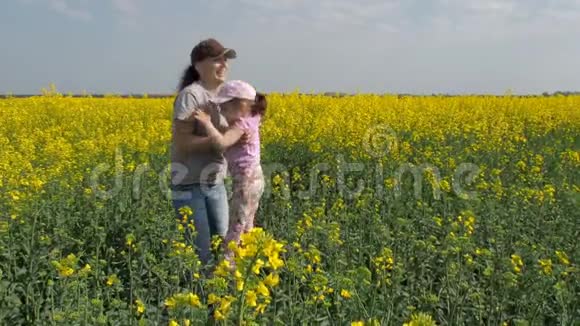 母亲在大自然中拥抱她的女儿带着小女孩在黄田的女人一个幸福的家庭视频的预览图