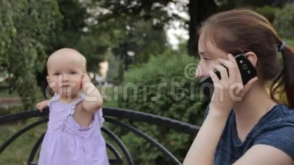 一个女佣在电话里四处张望一个穿着紫色斑点连衣裙的小女孩用耳朵握着她的手视频的预览图