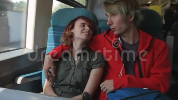 年轻漂亮快乐的时髦夫妇坐在火车旁望着窗户思考着他们在火车上的生活视频的预览图