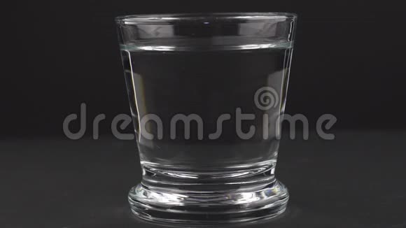一片泡腾的止痛片落入玻璃杯中在黑色背景下溶解慢镜头的阿司匹林视频的预览图