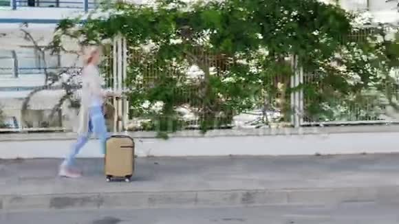 带着旅行袋的女人沿着度假区走它沿着篱笆走篱笆上长满了常春藤视频的预览图
