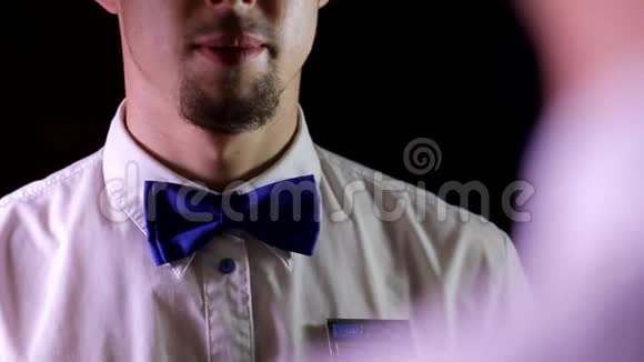 年轻英俊雄心勃勃的男影院电影院工作人员穿着干净的白领衬衫检查调整蓝色领结视频的预览图