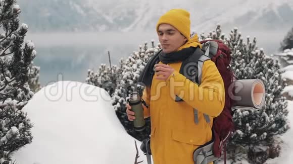 冬天美丽的山穿着黄色冬装的徒步旅行者在外面喝热茶或咖啡视频的预览图