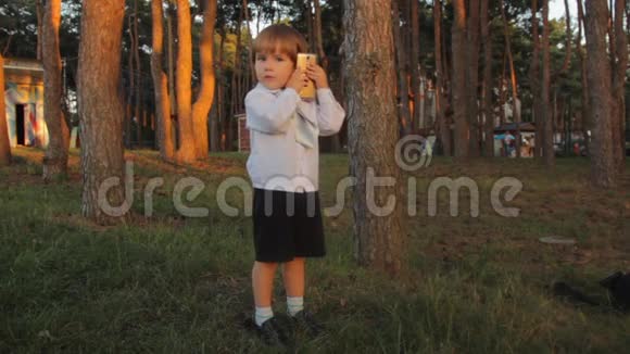 一个穿着黑色马裤的小男孩一件带领带的白色衬衫打开一个电话把智能手机从一只耳朵按到另一只耳朵视频的预览图