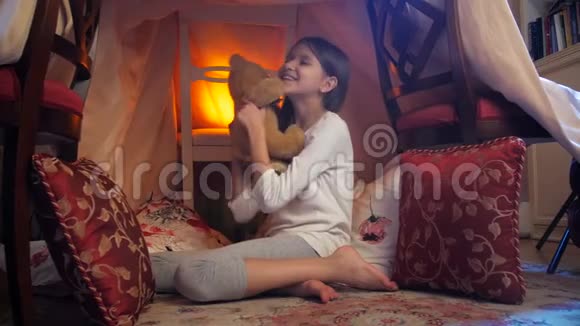 晚上穿睡衣的可爱女孩在自制帐篷里玩玩具熊的4k娃娃视频视频的预览图