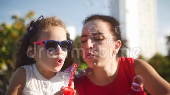 快乐的妈妈和孩子在公园里吹肥皂泡慢动作库存录像慢动作视频的预览图