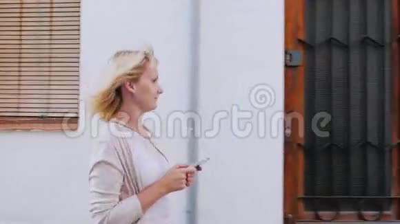 年轻女子带着电话走在欧洲老城区狭窄的街道上视频的预览图