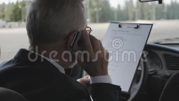 老人正在研究文件坐在车里打电话很忙的商人视频的预览图