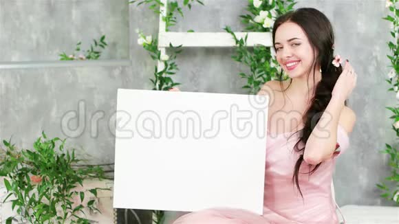 年轻女子在春季拍照时摆姿势白色背景绿色植物视频的预览图