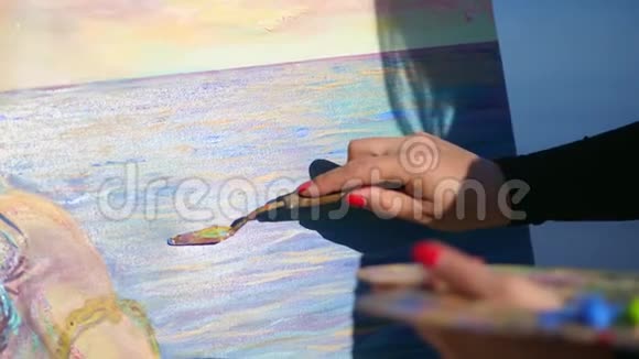 夏天户外特写女手的艺术家她用一个特殊的小铲把颜料涂在画布上视频的预览图