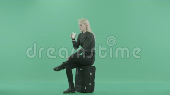 一个女人坐在行李上喝咖啡视频的预览图