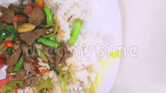 有人用叉子吃饭用肝脏吃米饭在白色的盘子上看食物视频的预览图