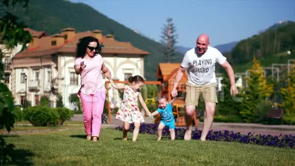 无忧无虑的年轻家庭幸福地沿着绿草牵着手幸福地面对着家人视频的预览图
