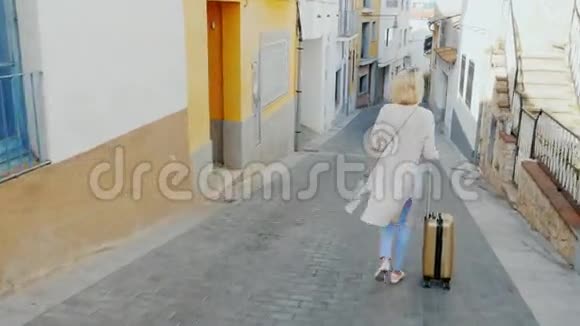 带着旅行袋的女游客沿着西班牙老欧洲城市的狭窄街道走去视频的预览图
