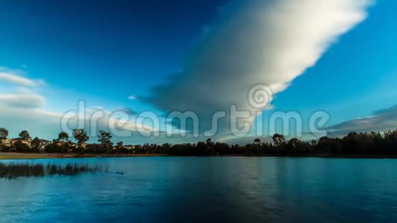 巨大的白色风暴雨云在深蓝的天空中移动在4K时间流逝的自然公园的镜面湖上视频的预览图